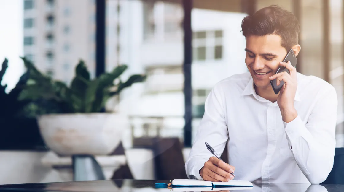 Mężczyzna robiący notatki podczas rozmowy telefonicznej